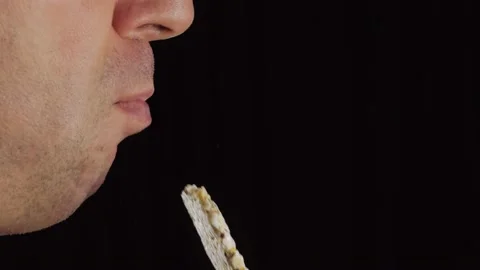 Close-up of a man's face biting into a crusty whole grain bread. Vídeo Stock 169235557