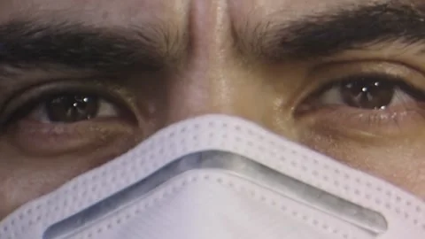 Close-up of man's face with a face mask, brown eyes, serious look Stock Footage 132212723