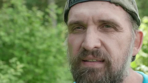 Close up of man's face with green trees and grass on background. Mans looks Stock Footage 135579873