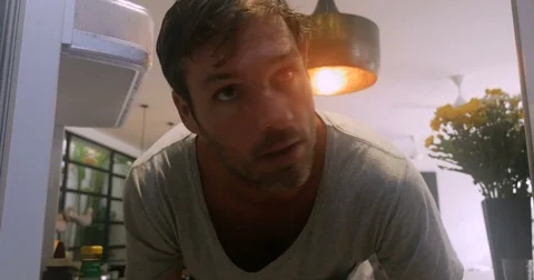 Close up of a man's face as he opens the refrigerator and can't find something Stock Footage 84911636