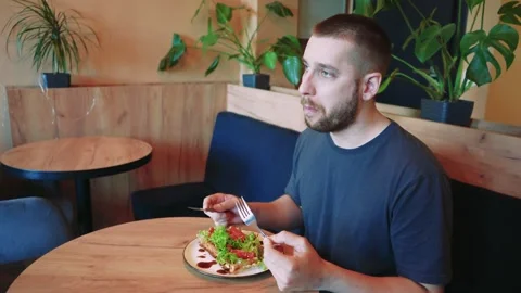 Close-up of a man's face, raising a fork with food to his mouth. A boy enjoys Stock Footage 292644305