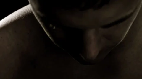 Close up of a man's face while he working out in the shadows of a dark gym Stock Footage 33831023