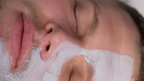 Close-up of a man's face while putting a mask on a man's face. Men's skin care Vídeo Stock 250356408