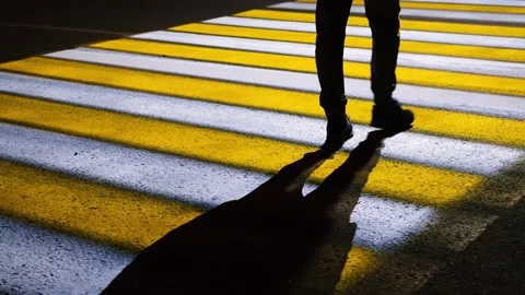 Close-up of a man's feet walking on a modern luminous road crosswalk at night Stock Footage 162496167