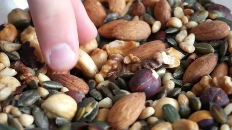 Close-up of a man's fingers taking a nut from a pile of different nuts Stock Footage 146695284
