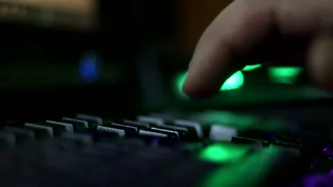 A close-up of a man's fingers typing on a glowing keyboard. 库存影片 333707036