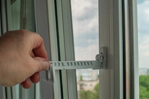 Close-up of a man's hand adjusting a window opening limiter. Window stop ad.. Stock Photos