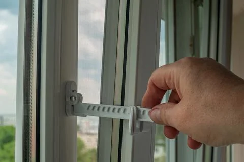 Close-up of a man's hand adjusting a window opening limiter. Window stop ad.. Stock Photos