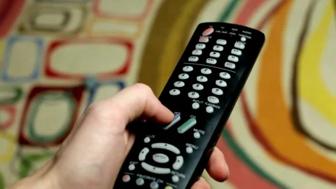 Close-up of a man's Hand and the TV Remote. The Hand Presses the Buttons on.. Stock Footage 257875437