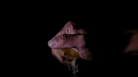Close-up of a man's hand on a black background squeezes citrus fruit, lemon. Stock Footage 265840572