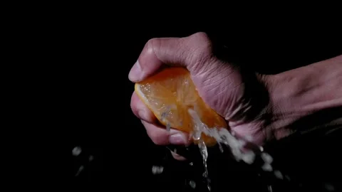 Close-up of a man's hand on a black background squeezes citrus fruit, lemon. Stock-Footage 336588840