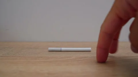 A close-up of a man's hand breaking in half a white cigarette on a table against Stock Footage 203212304