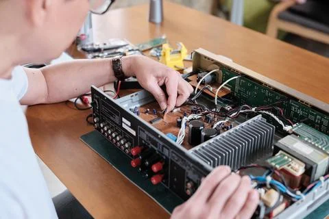 Close-up, man's hand checking audio equipment circuit board for wiring repair. Stock Photos