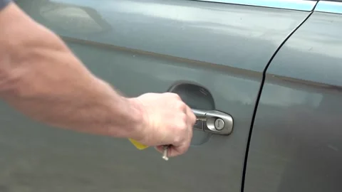 Close-up of man's hand closes with key the grey car door. Slow motion Vidéo 208295312