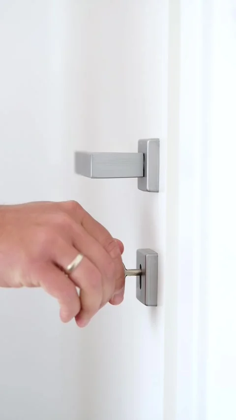 Close up of man's hand closing white door and turning key twice in keyhole Stock Footage 279983193
