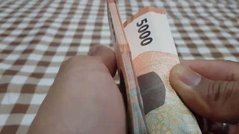 Close-up of a man's hand counting a stack of Five thousand rupiah notes. a .. Stock Footage 270441732
