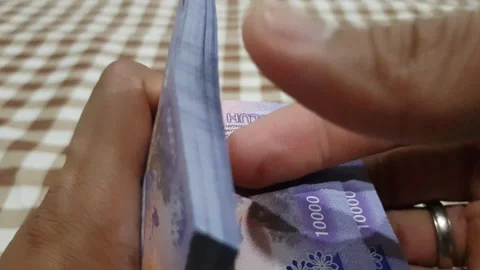Close-up of a man's hand counting a stack of ten thousand rupiah notes. a b.. Stock Footage 270441749