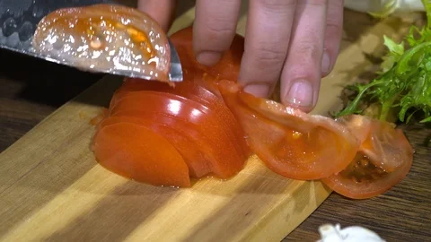 Close-up of a man's hand that cuts a fresh tomato on a wooden board Vídeos de archivo 87996652