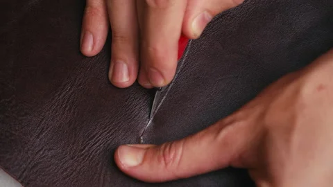 Close up man's hand cuts leather fabric with special knife. Craft production Stock-Footage 138308133