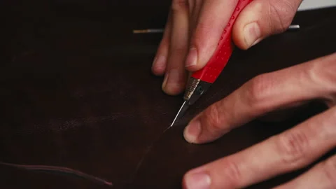 Close up man's hand cuts leather fabric with special knife. Craft production Stock Footage 138339665