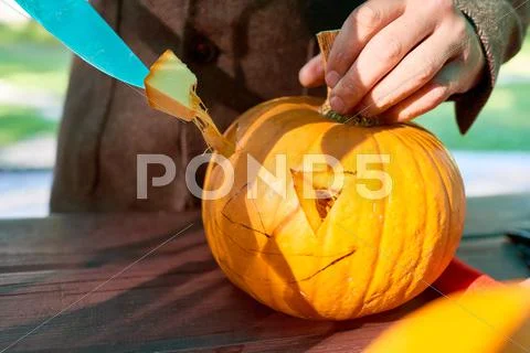 Close up of man's hand cutting with knife a pumpkin as he prepares a jack-o-lant Stock Photos