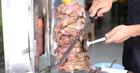Close up of man's hand cutting skewered meat- traditional shawarma or kebab on Stock-Footage 151471859