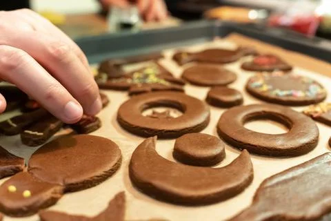 Close-up of a man's hand decorates a festive gingerbread cookie before baking Stock Photos