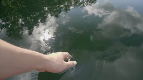 Close up of a man's hand dips his hand into the lake. 库存影片 155247521