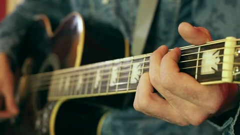 Close-up of a man's hand doing the chords on the fretboard of an acoustic guitar Stock Footage 248528614