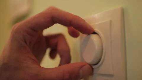 Close-up of a man's hand effortlessly adjusting a wall-mounted dimmer switch Stock Footage 327158494