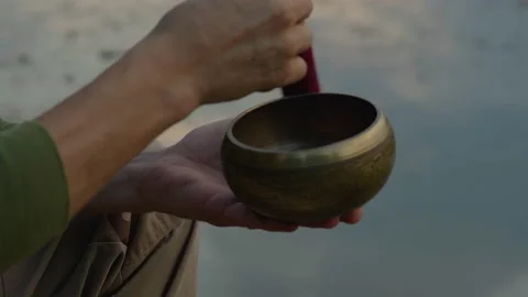 Close-up, a man's hand extracts sounds from a singing bowl against the backdrop Stock Footage 228017516