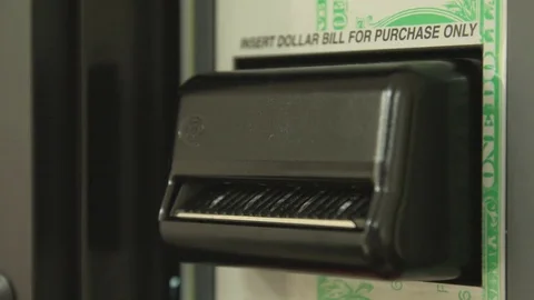 Close up of a man's hand feeding a dollar bill into an automated vending machine 動画素材 75058937