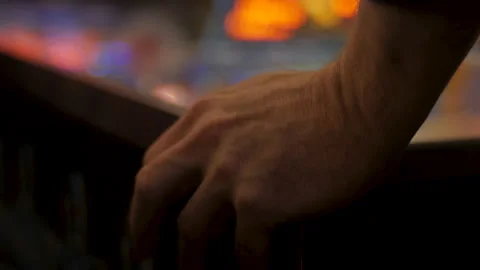 Close-up of a man's hand hitting the flipper buttons of a pinball table Stock-Footage 130990152
