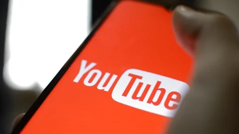 Close-up man's hand hold iphone with youtube app on the display. Stock Footage 229114155