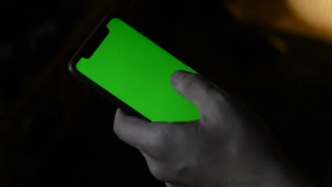Close-up man's hand holding apple iphone with green screen in a dark background Stock-Footage 200816899