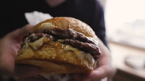Close-up of a man's hand holding a big mouth-watering juicy Burger. Stock Footage 106135545