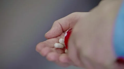 Close-up of a man’s hand holding many pills poured from a medicine jar. Video stock 323461554