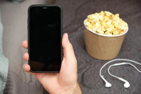 Close up mans hand holding a mobile phone with copy space with earphones and Stock Photos