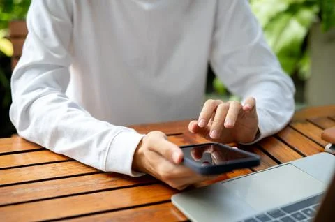 Close up of man's hand holding using phone over laptop while sitting outdoo.. Foto stock