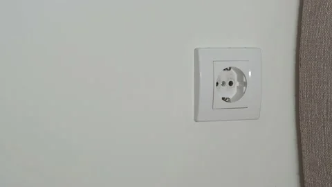 A close-up of a man's hand inserts a black wire to power a white rosette against Stock Footage 202172646