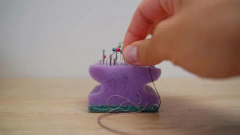 A close-up of a man's hand inserts small metal pins on a white background into a Stock Footage 203211924