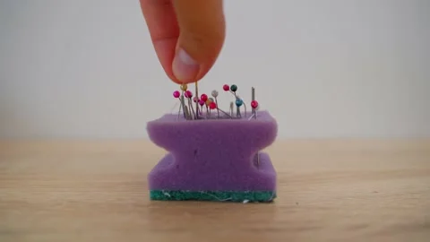 A close-up of a man's hand inserts small metal pins on a white background into a Stock Footage 203212380