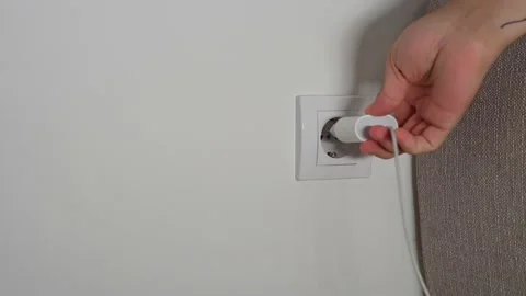 A close-up of a man's hand inserts a white power adapter to charge the phone Stock Footage 202143335