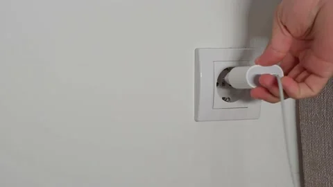 A close-up of a man's hand inserts a white power adapter to charge the phone Stock Footage 202172631