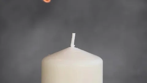 Close-up man's hand lighting a candle. White candle Fire Wick at gray background Stock Footage 127283727