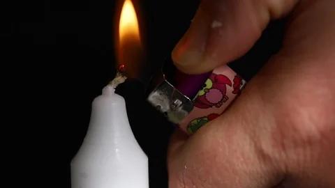 Close up of a man's hand lighting a white candle on black background Stock Footage 106492125