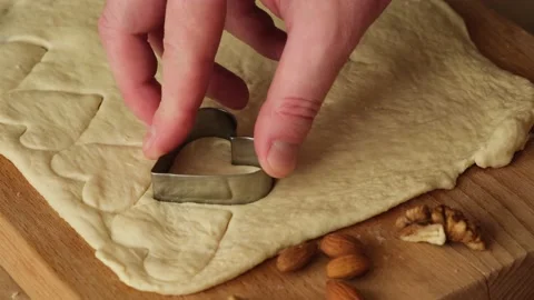Close up man's hand making cookies, cutting hearts from dough on kitchen table. Stock Footage 169460668