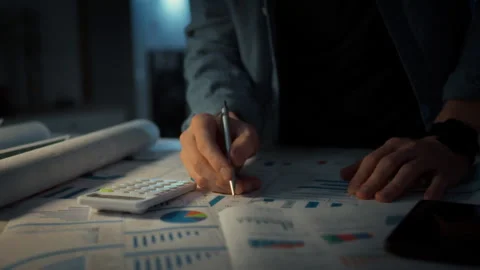 Close-up of a mans hand marking errors with a pen on paper business charts. Stock Footage 348319619