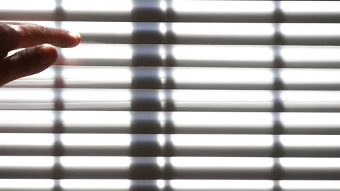 Close up man's hand moves towards closed bright sun lit Venetian blinds, opens 库存影片 128640524