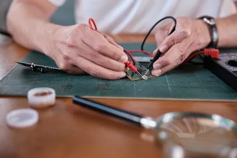 Close-up, man's hand with multimeter tool, circuit board voltage test. Stock Photos